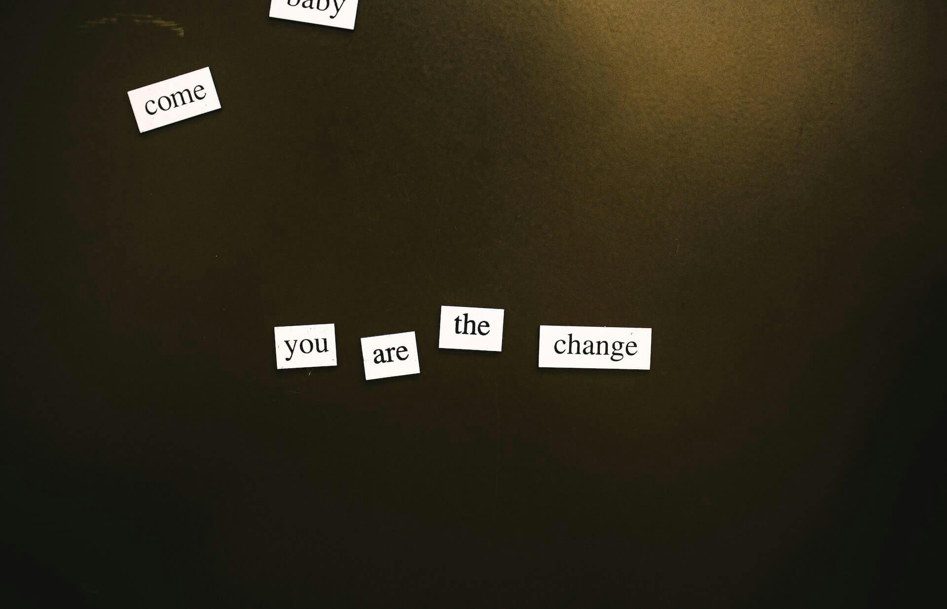 Pedaços de papel com palavras formando a frase "Come baby, you are the change"