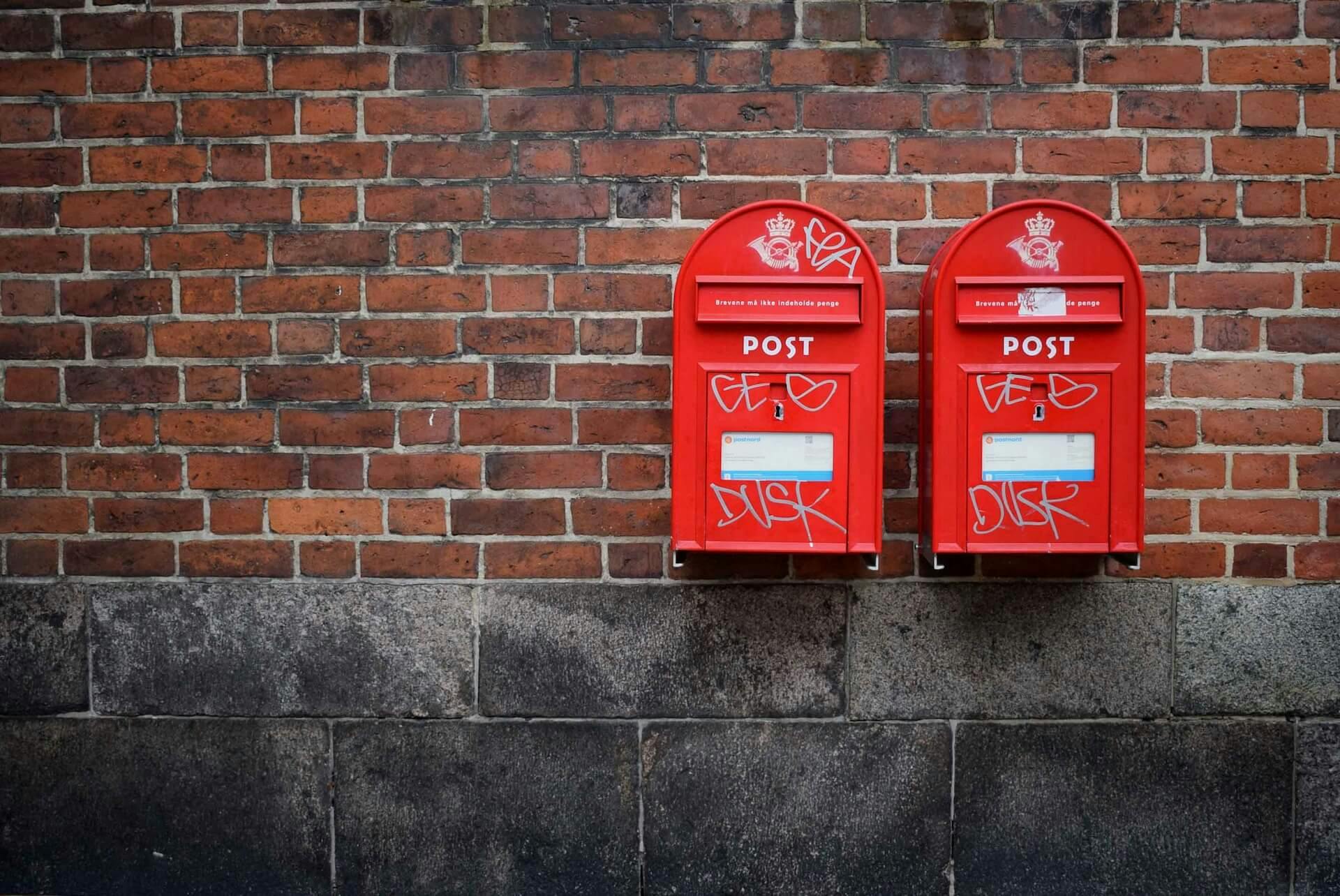 uma parede de tijolos com duas caixas postais penduradas